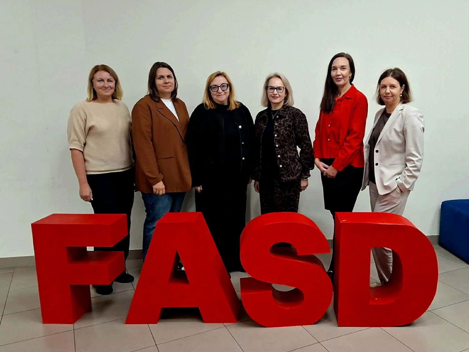 Švietimo pagalbos tarnybos specialistės su renginio dalyvėmis stovi prie FASD raidžių